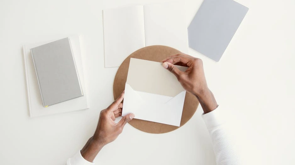 Masanın üzerinde duran bir deftere not alan kişi